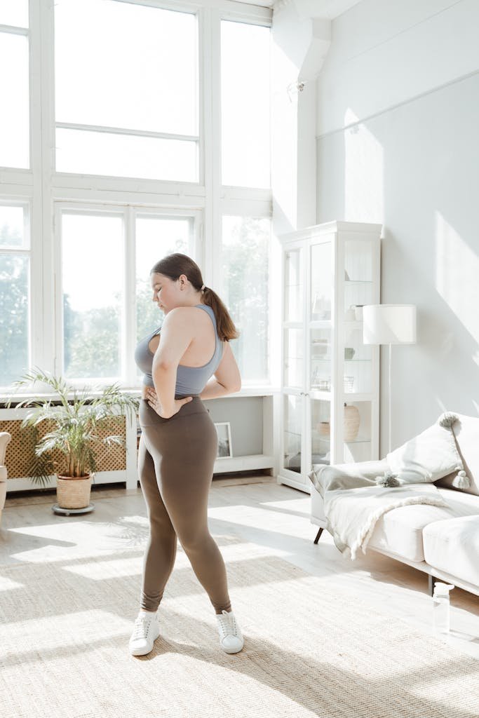 Confident plus size woman practicing yoga in a bright, serene living room.