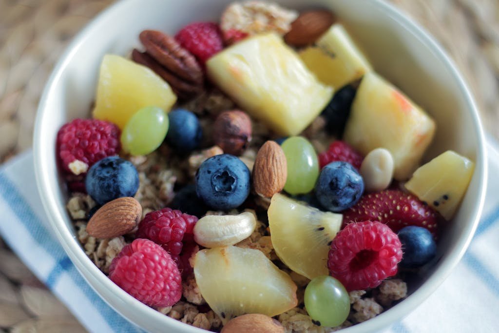 Close-up of a colorful muesli bowl with fresh berries, nuts, and pineapple.