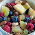 Close-up of a colorful muesli bowl with fresh berries, nuts, and pineapple.