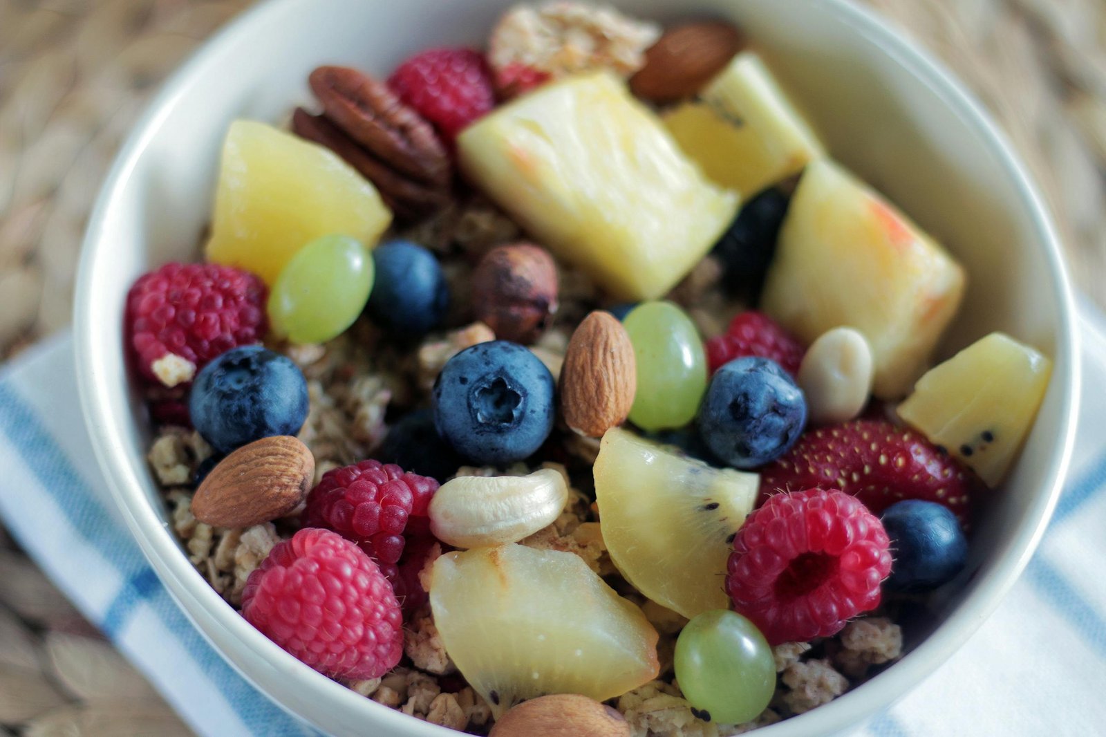 Close-up of a colorful muesli bowl with fresh berries, nuts, and pineapple.